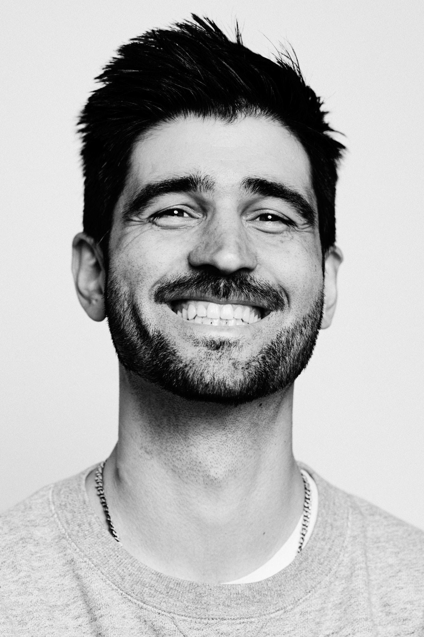 Schwarz-Weiß-Porträt eines lächelnden Mannes mit Bart.