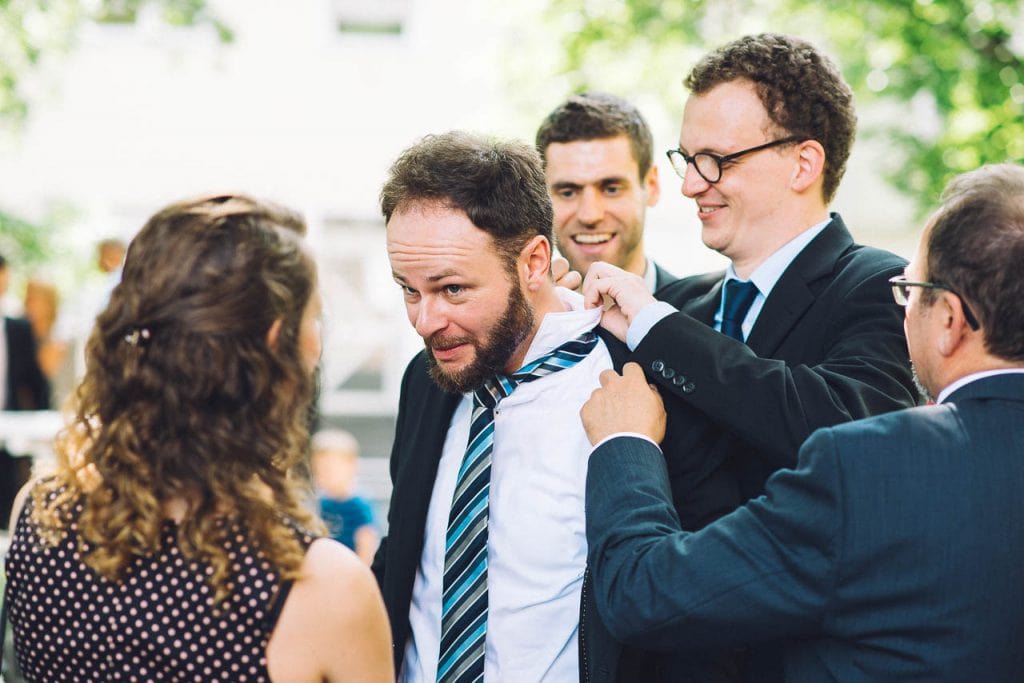 Ein Hochzeitsgast bekommt Hilfe mit seiner Krawatte.