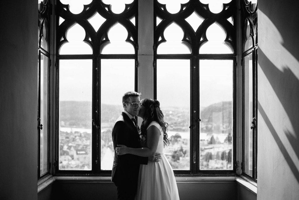 Das Brautpaar im Schloss vor einem Fenster.