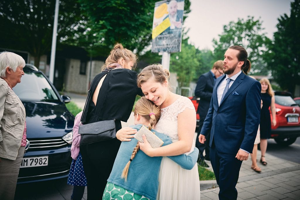 Die Braut umarmt die ankommenden Hochzeitsgäste.