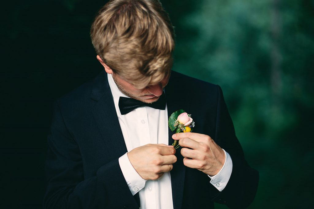 Der Bräutigam richtet seine Ansteckblume. 