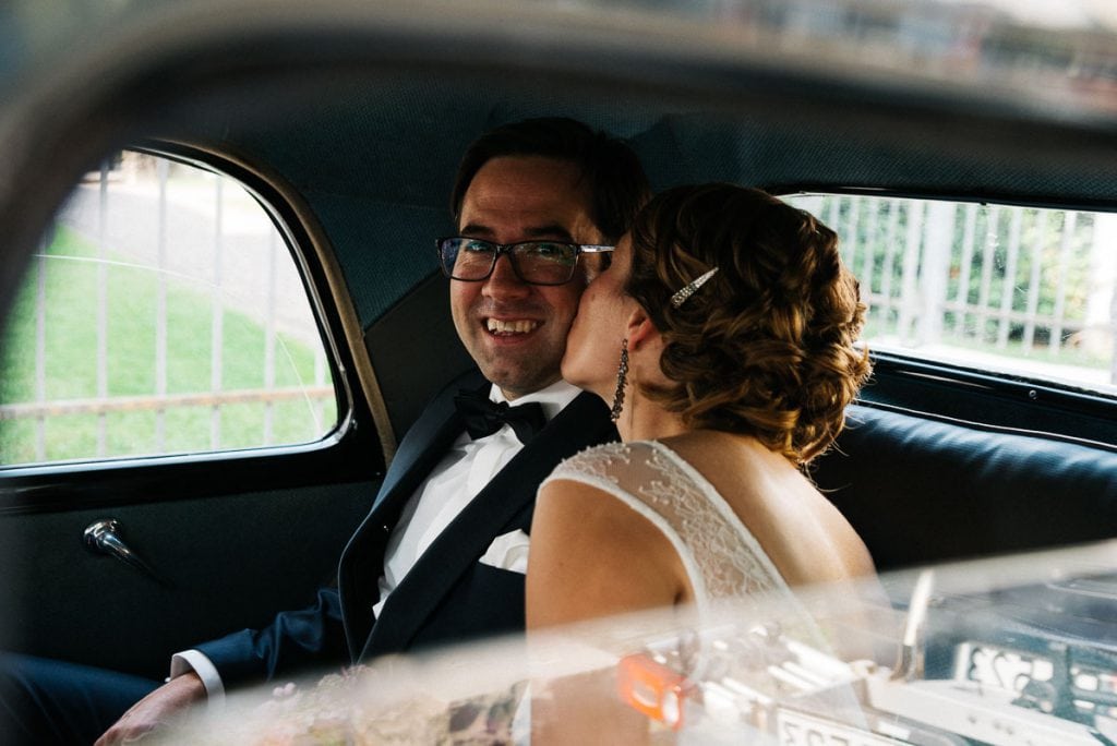 Die Braut küsst den Bräutigam im Hochzeitsauto.