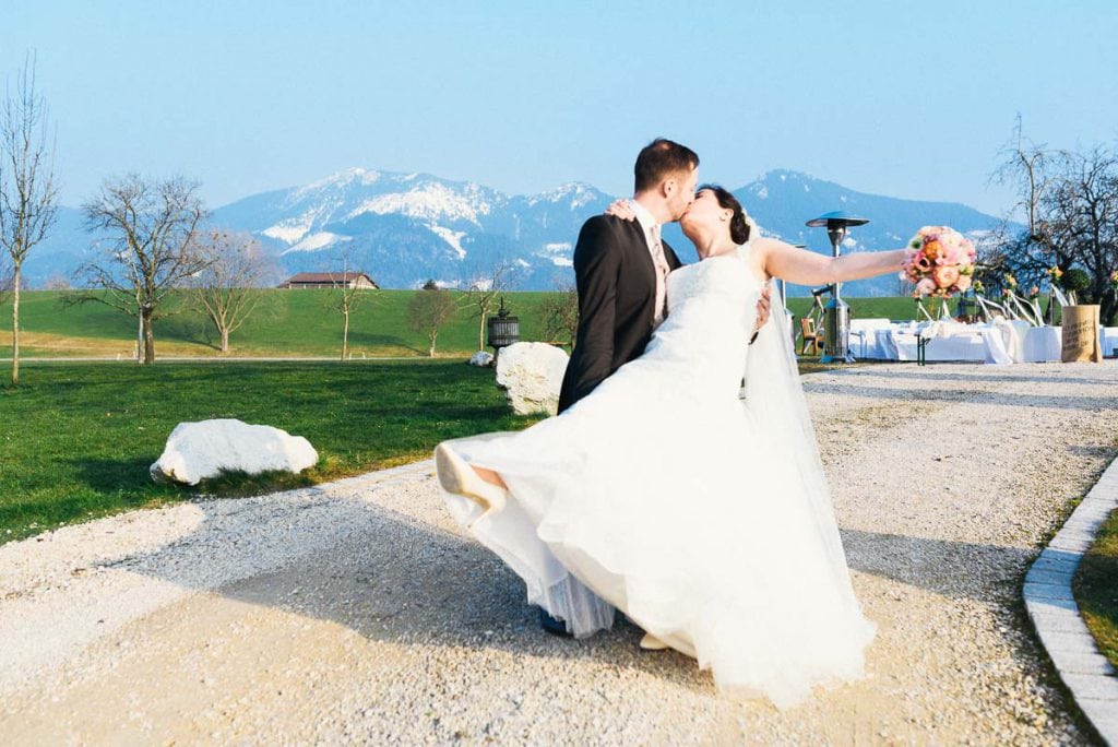 Das Brautpaar küsst sich vor den Alpen.