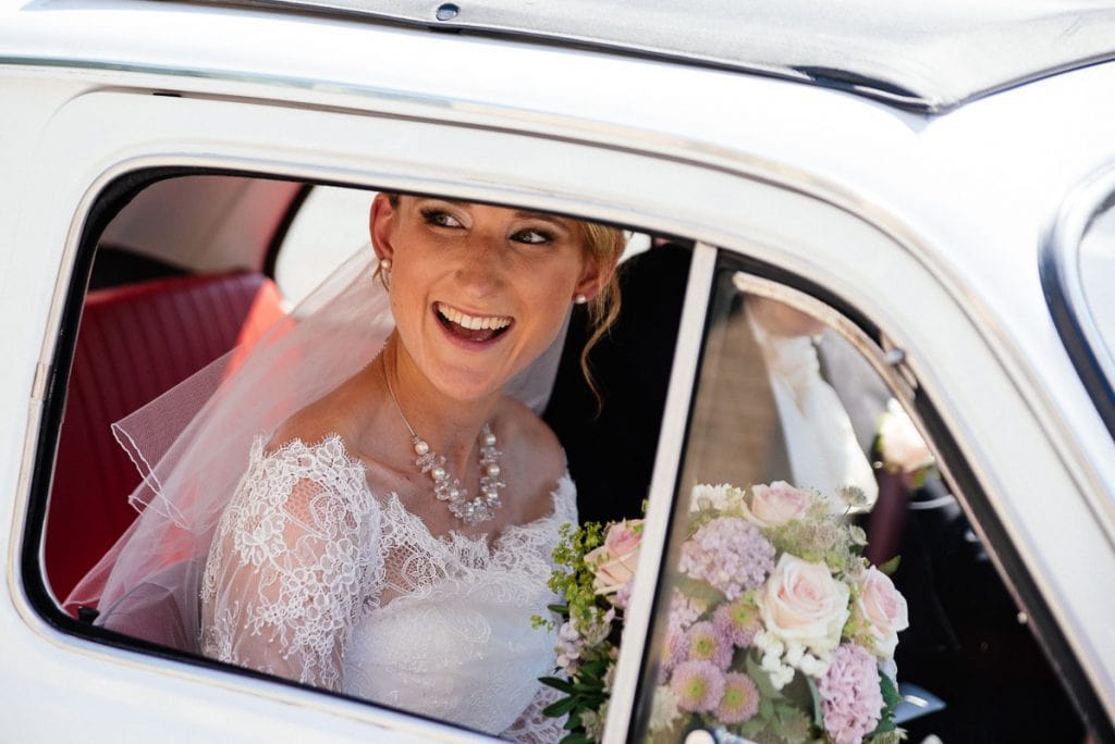 Die Braut schaut durchs Autofenster.