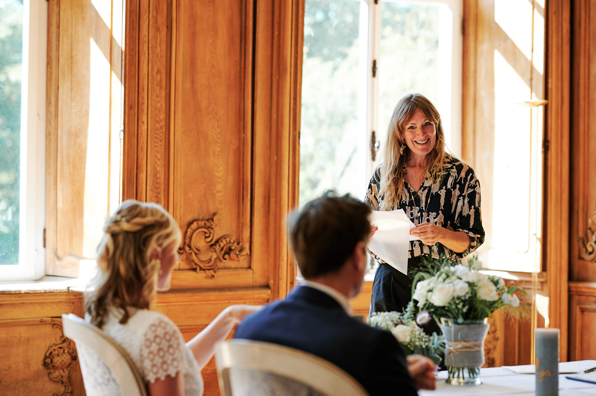 Frau hält eine Rede auf einer Hochzeit in Schloss Wissen, während die Gäste zuhören.