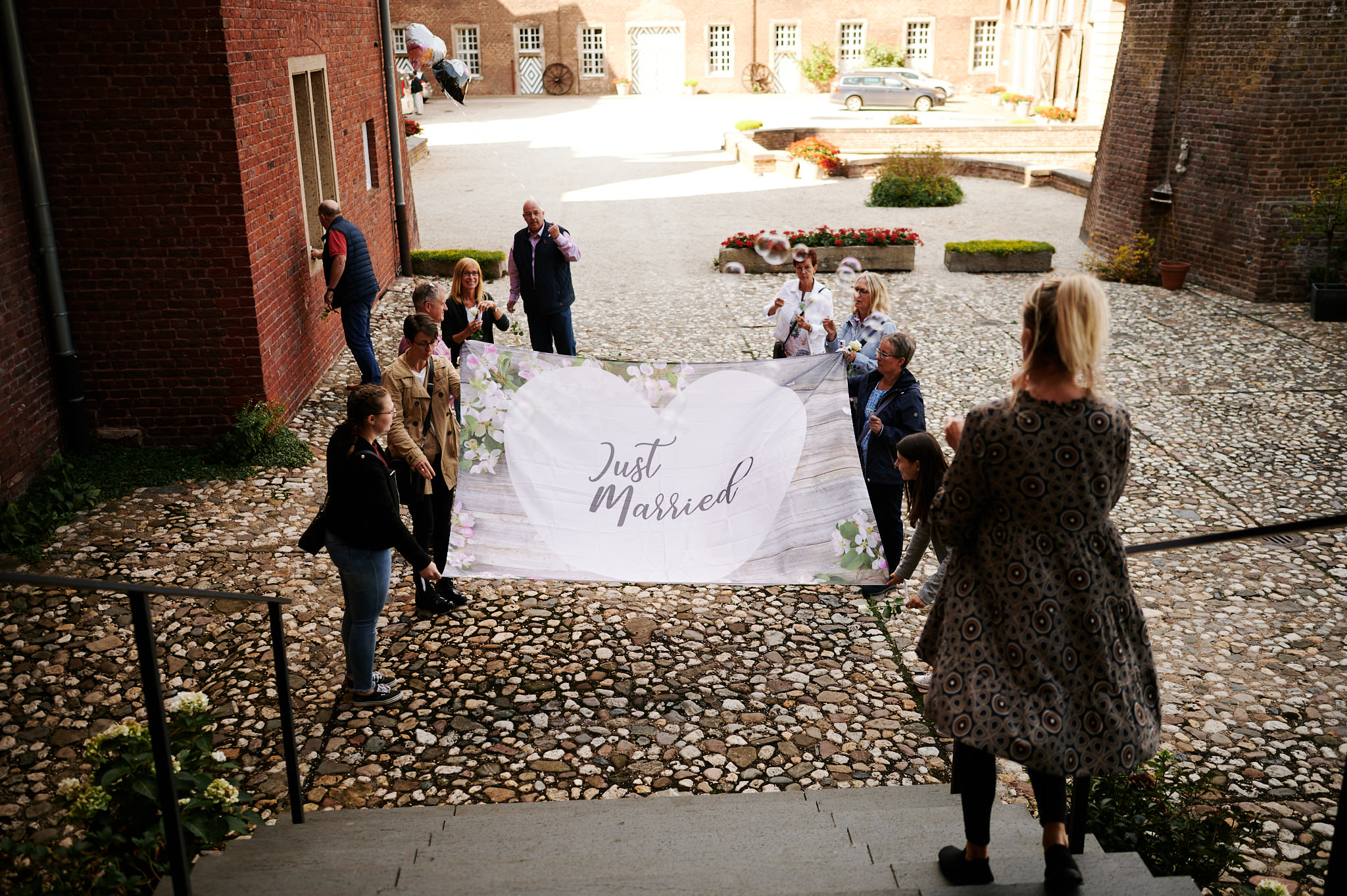Gäste halten bei einer Hochzeitsfeier ein „Frisch verheiratet“-Banner in der Hand.