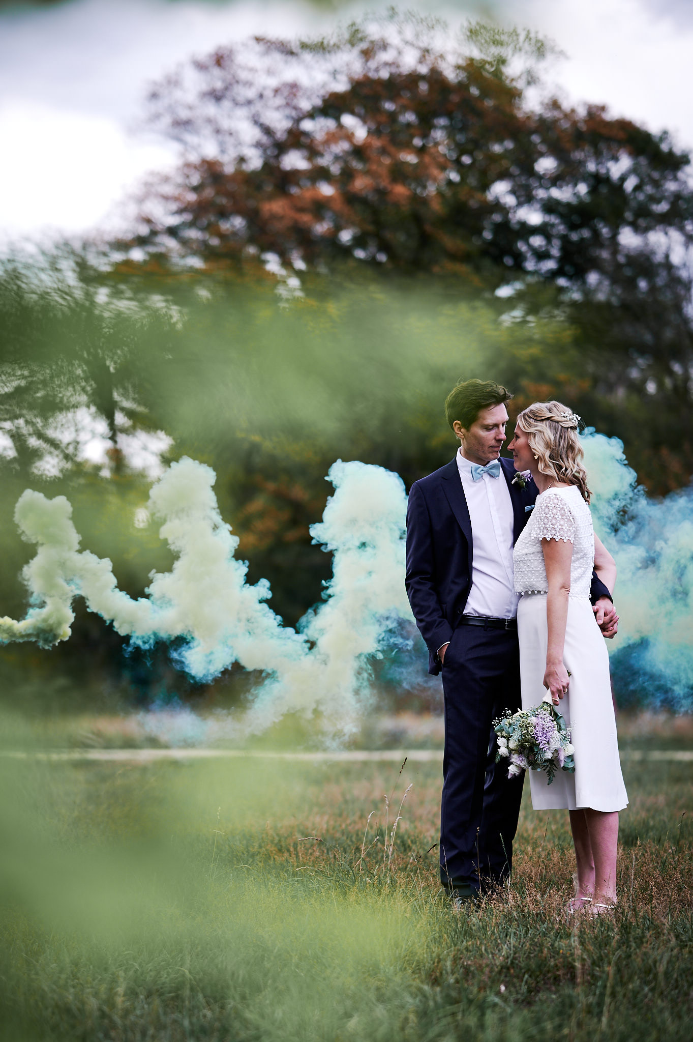 Eine Braut und ein Bräutigam stehen zusammen mit blauem Rauch im Hintergrund bei ihrer Schlosshochzeit.