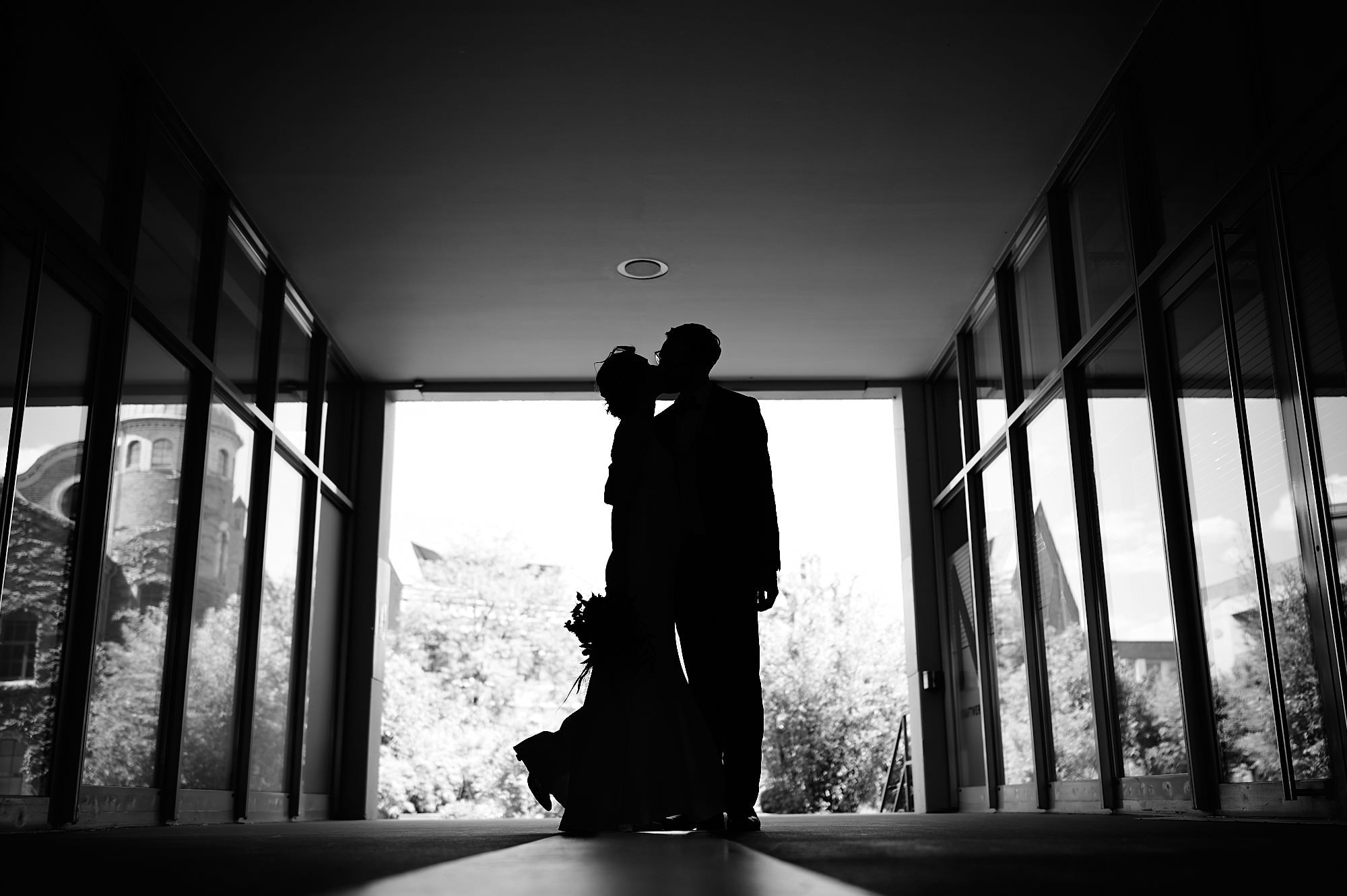 Silhouette eines Paares, das sich in einem sonnenbeschienenen Durchgang küsst.