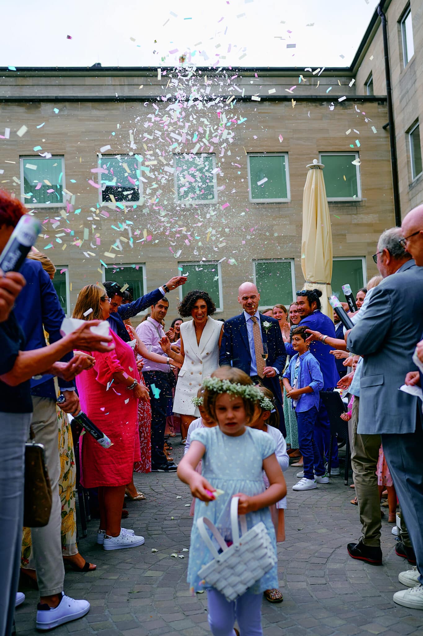 Ein Brautpaar geht während einer Hochzeitsfeier mit in die Luft geworfenem Konfetti durch eine Menschenmenge von Gästen und fängt atemberaubende Hochzeitsbilder ein.