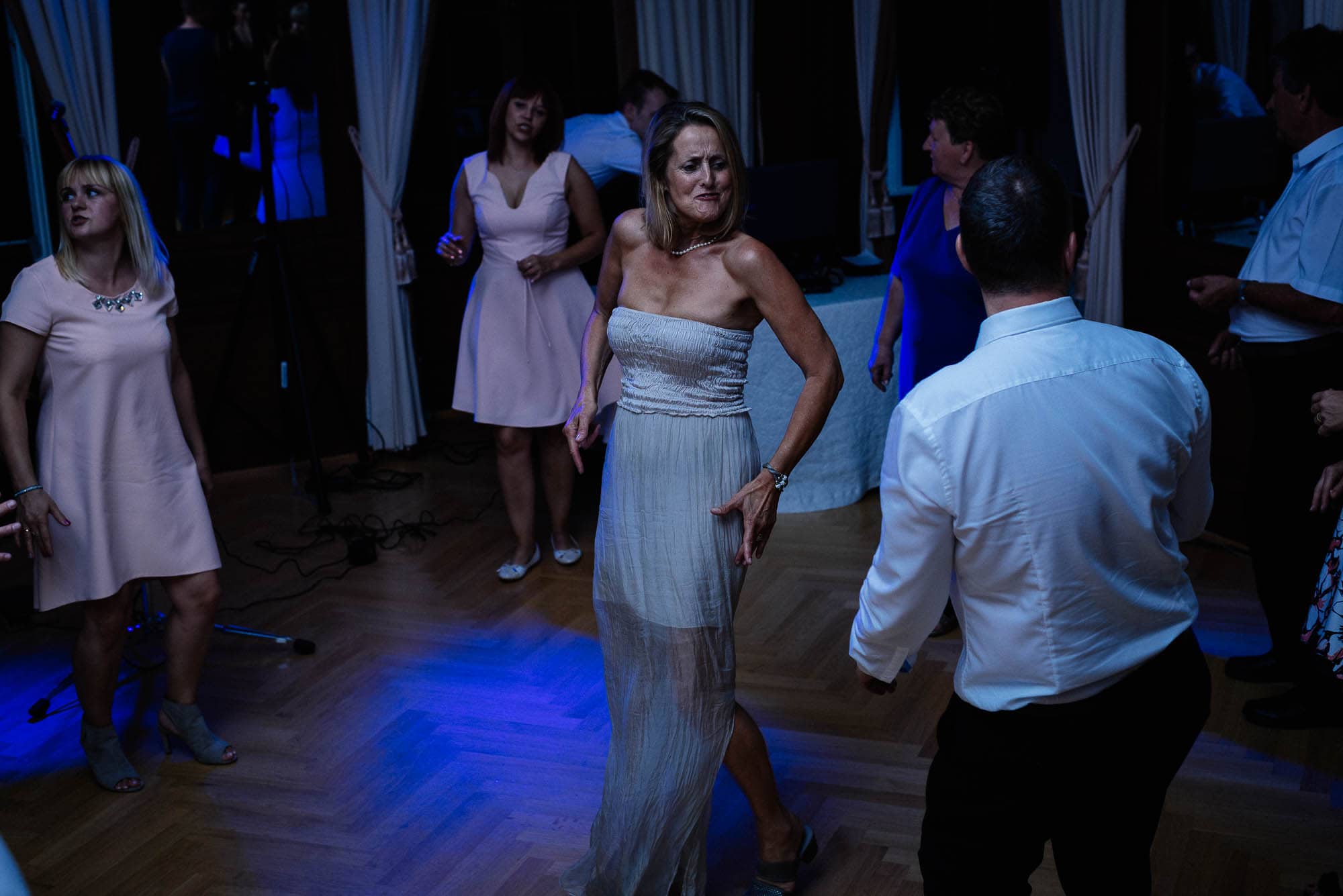Menschen tanzen bei einer Veranstaltung mit gedämpftem blauem Licht und machen atemberaubende Hochzeitsbilder.