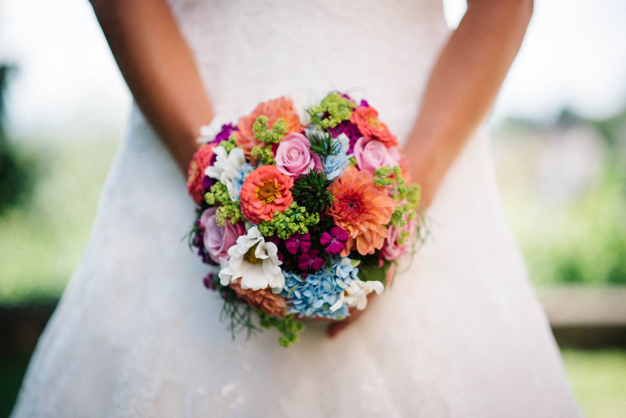 Braut hält einen bunten Blumenstrauß in ihren Hochzeitsbildern.